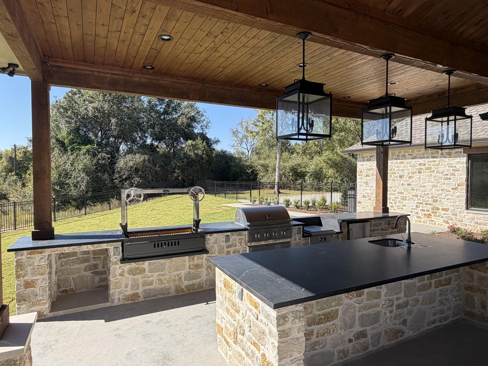 Covered outdoor kitchen with a stone base and dark granite countertop